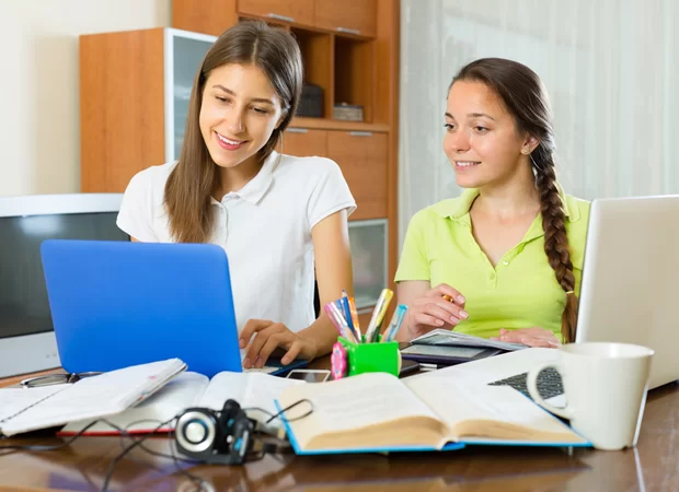 Zwei junge Frauen schauen zusammen auf einen Laptop