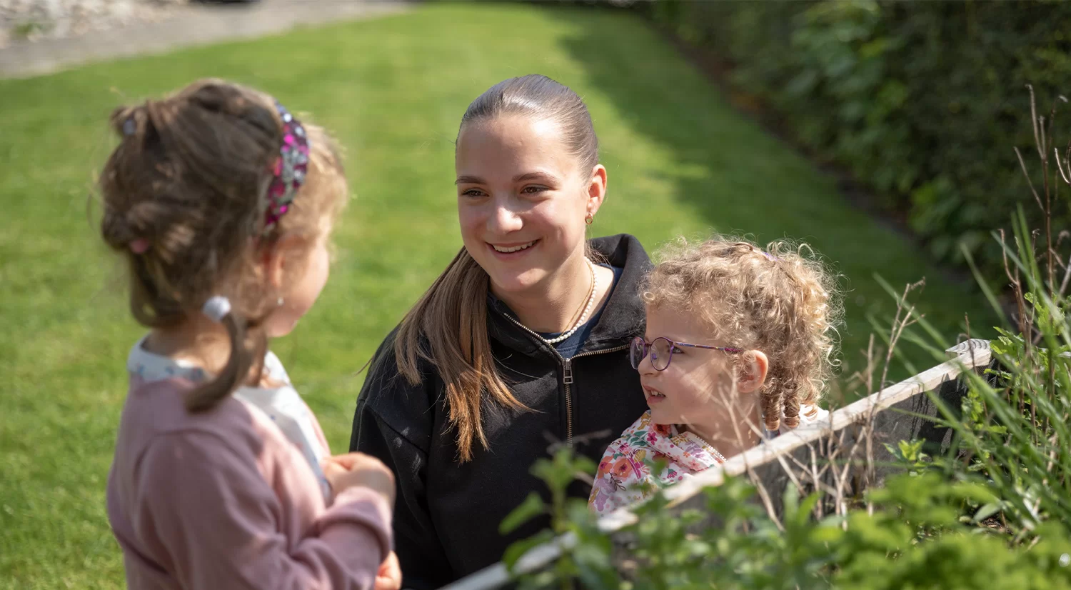 Eine Frau steht in einem Garten mit zwei Kindern